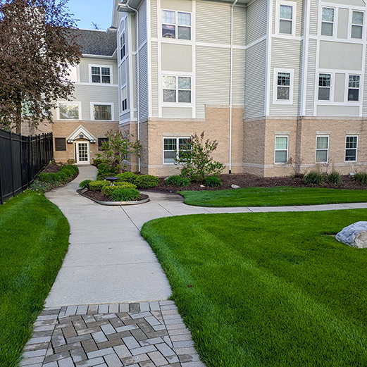 Walking paths outside University Senior Living, landscaped with mulch beds, foliage and trees.